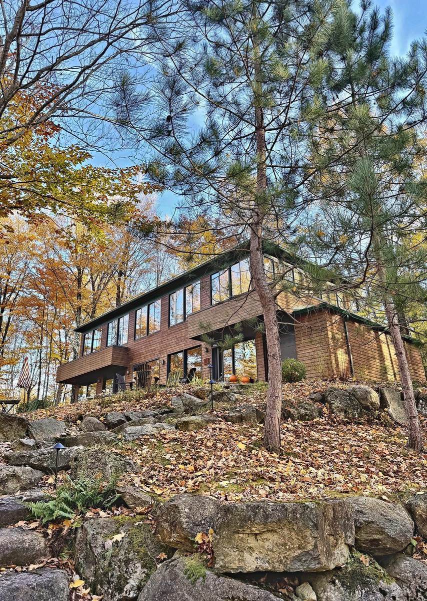 Le chalet vu du bas du terrain, entre les pins et les rochers.